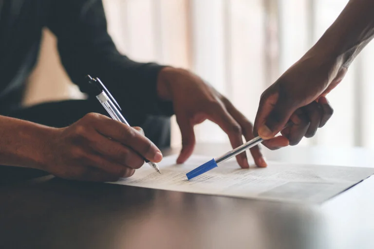 Cropped shot of an unrecognizable man filling a document with the help of a financial advisor at home business law proto law firm